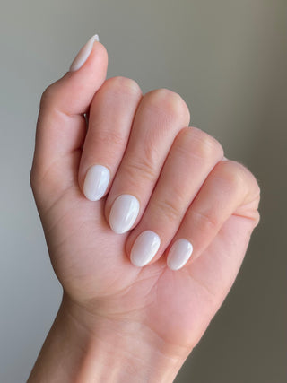 Les press on nails sans colle sur cette main sont de couleur blanche, style mily, ronds et courts.