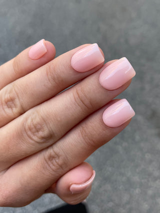 Les ongles que le modèle portent sont des faux ongles de couleur nude beige et de forme carrée et de longueur courte.