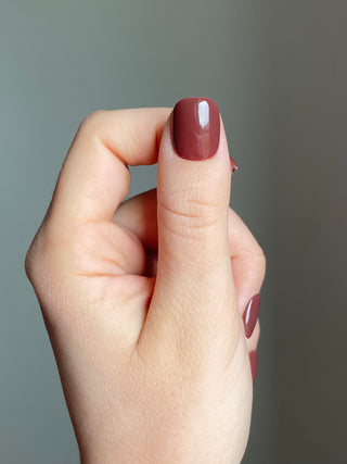 Press on nails sans colle, couleur nude marron unie et de longueur extra-court portés sur le pouce.